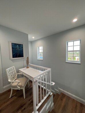 Cozy retreat with a crib, chair, and table, offering a view of palm trees outside.