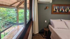 A room with a bed, a hammock, and a view of greenery outside. - Green Area House (Angra dos Reis)