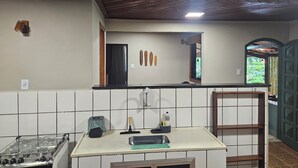 A kitchen with a gas stove, a sink, a countertop, and a window with a view of greenery. - Green Area House (Angra dos Reis)