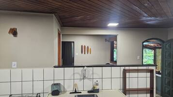 A kitchen with a gas stove, a sink, a countertop, and a window with a view of greenery.