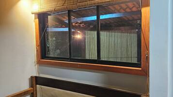 A room with a wooden ceiling, a window with blinds, a wooden bench, and a wall-mounted light fixture.