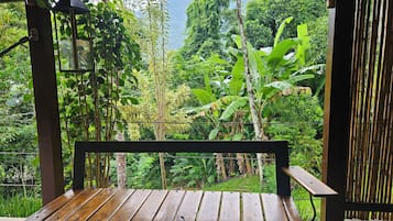 A wooden bench with a view of lush greenery and mountains.