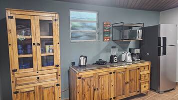 A kitchen with wooden cabinets, a refrigerator, a microwave, and a window with curtains.