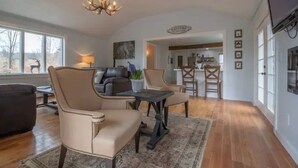 A spacious living room with a fireplace, a chandelier, and a view of the outdoors. - Inn at High Falls (High Falls)