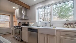 A kitchen with a stove, oven, dishwasher, and a window with a view of trees. - Inn at High Falls (High Falls)