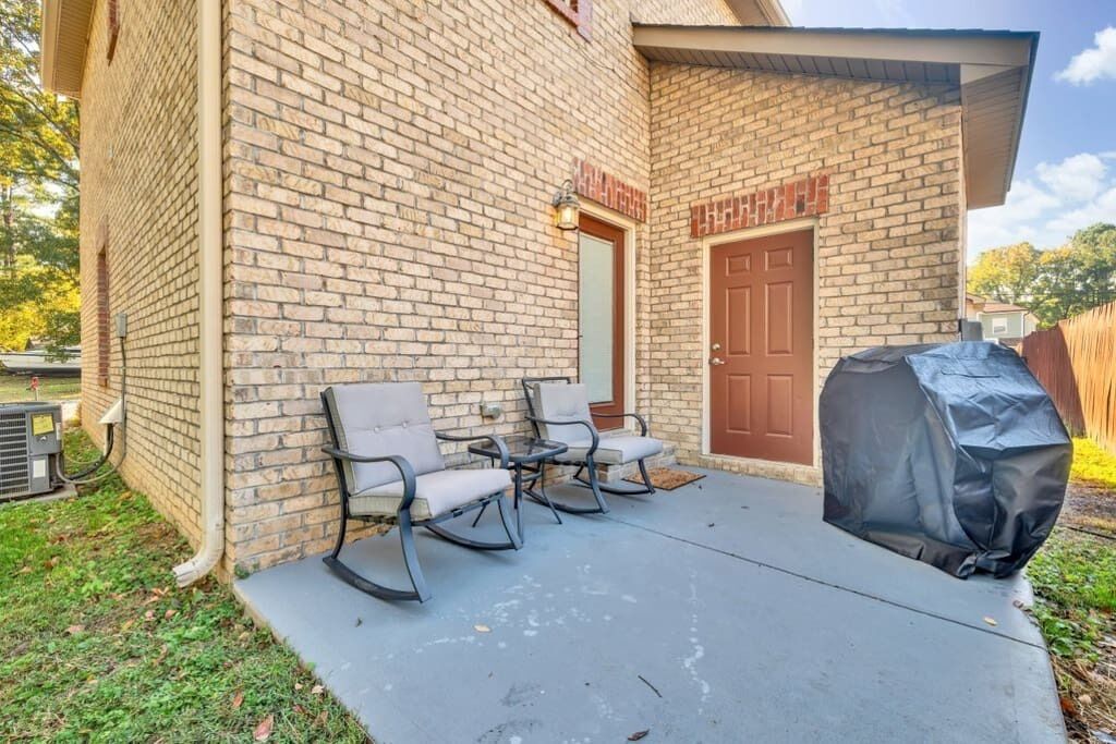 A brick building with a covered patio area, outdoor seating, and a barbecue grill.