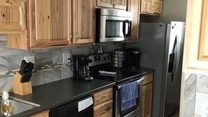 A kitchen with wooden cabinets, a stainless steel microwave, a refrigerator, a dishwasher, and a stove. - 2 BR, 1-1/2 bath house in wooded setting with private back yard, deck, hot tub. (Waynesville)