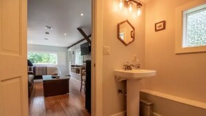 A bathroom with a white sink, a mirror, and a window.