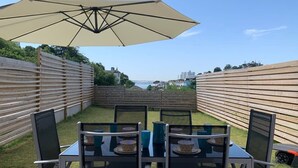 A patio with a table and chairs, an umbrella, and a view of the city. - The Mariners' Beacon Torquay (Torquay)