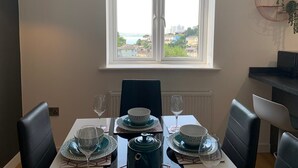A dining table set for four with a view of a cityscape through a window. - The Mariners' Beacon Torquay (Torquay)