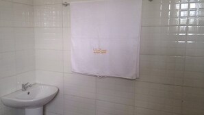 A bathroom with a white sink, a towel hanging on the wall, and tiled walls. - Spacious Serviced Apartments in Owerri,Accommodation Corporate and Private Stays (Owerri)