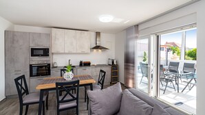 Eine moderne Küche mit grauen Schränken, einem Holzesstisch und einem grauen Sofa.
