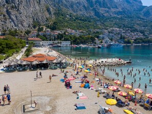 A beach with umbrellas, sun loungers, and people. - Beachfront penthouse Boho - Two Bedroom Apartment (Omis)