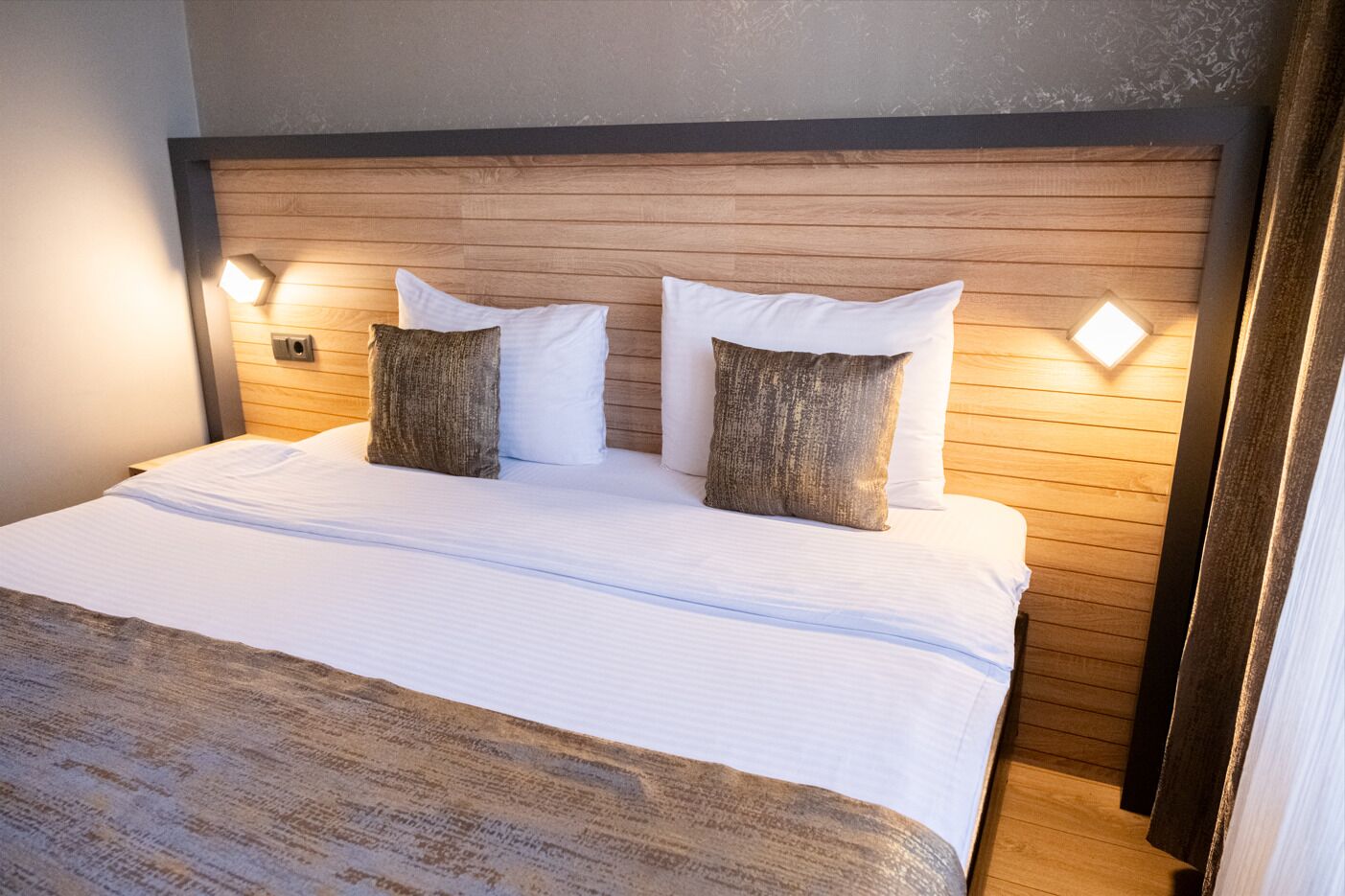 A bed with a wooden headboard, two pillows, and bedside lamps.