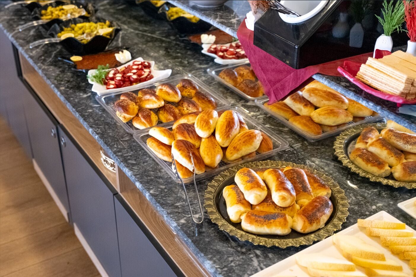 A buffet with various food items including bread, pastries, and a coffee machine.
