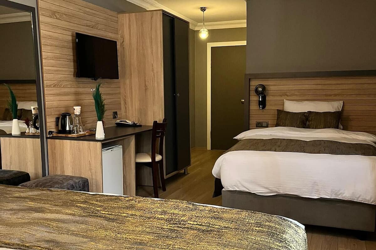A hotel room with a bed, a desk, a chair, a television mounted on the wall, and a mirror.