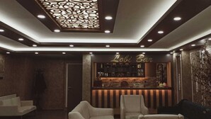 A bar area with a sign reading "Lobi Bar," featuring a bar counter, seating area with chairs, and decorative wall elements. - Çag Otel (Erzurum)