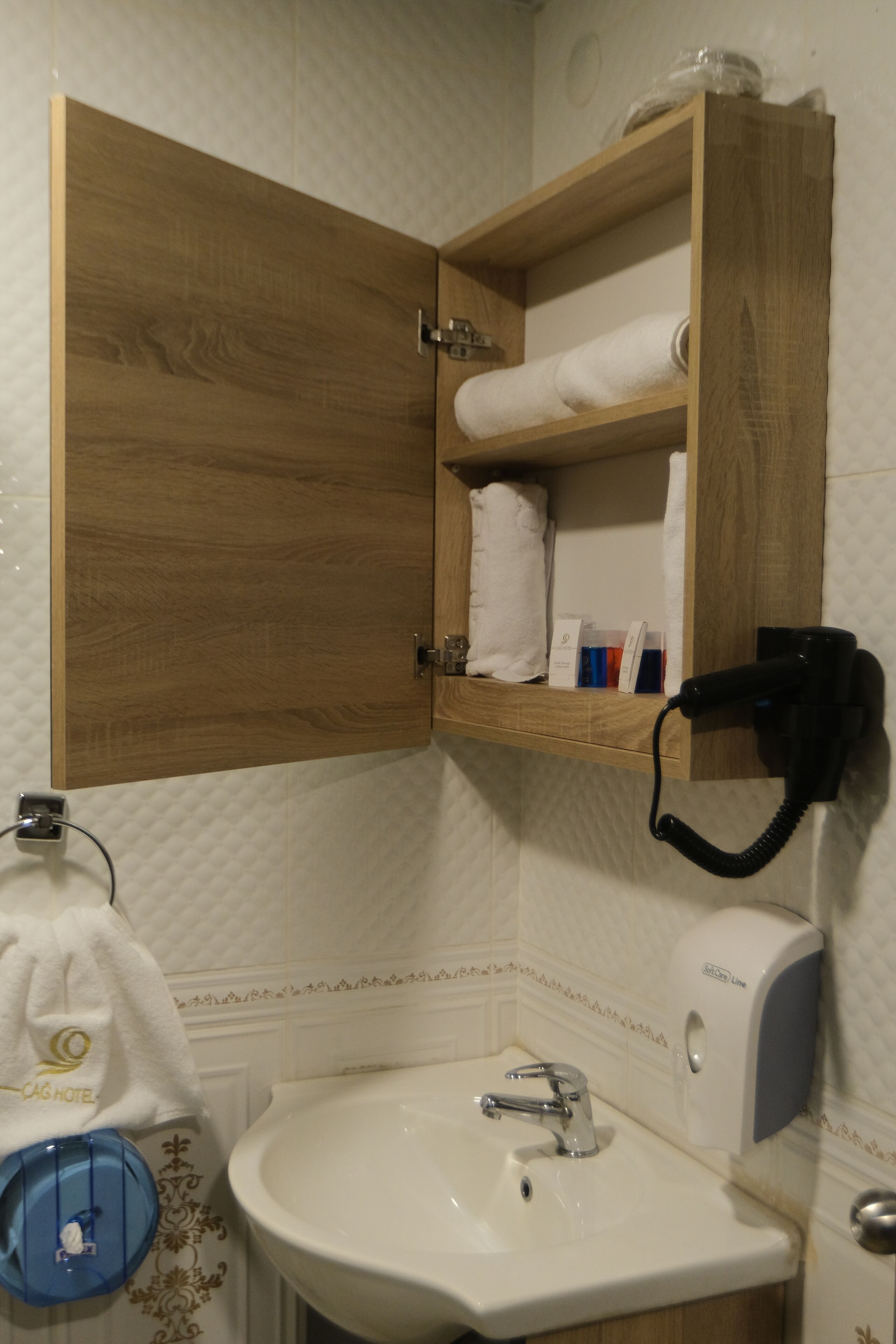 Un baño con un armario de madera, un lavabo y una toalla colgada en la pared.
