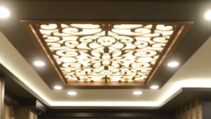 A reception desk with a decorative ceiling and a herringbone-patterned wall. - Çag Otel (Erzurum)
