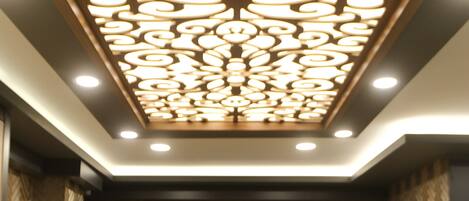 A reception desk with a decorative ceiling and a herringbone-patterned wall.
