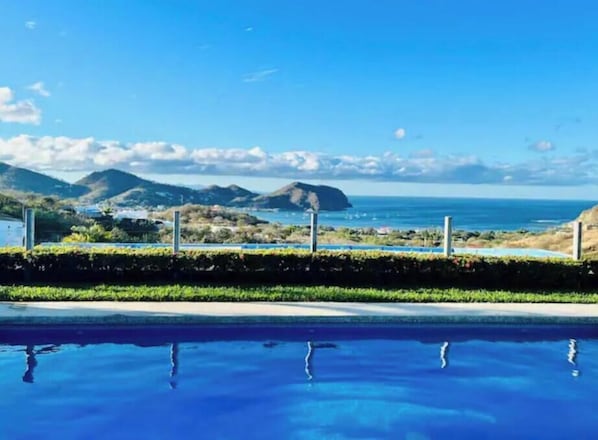 Ein Pool mit Blick auf das Meer und die Hügel.