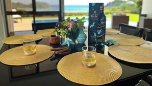 Une table à manger avec des sets de table, deux verres contenant un liquide transparent, une bouteille de whisky Blue Label et un vase décoratif avec des fleurs.