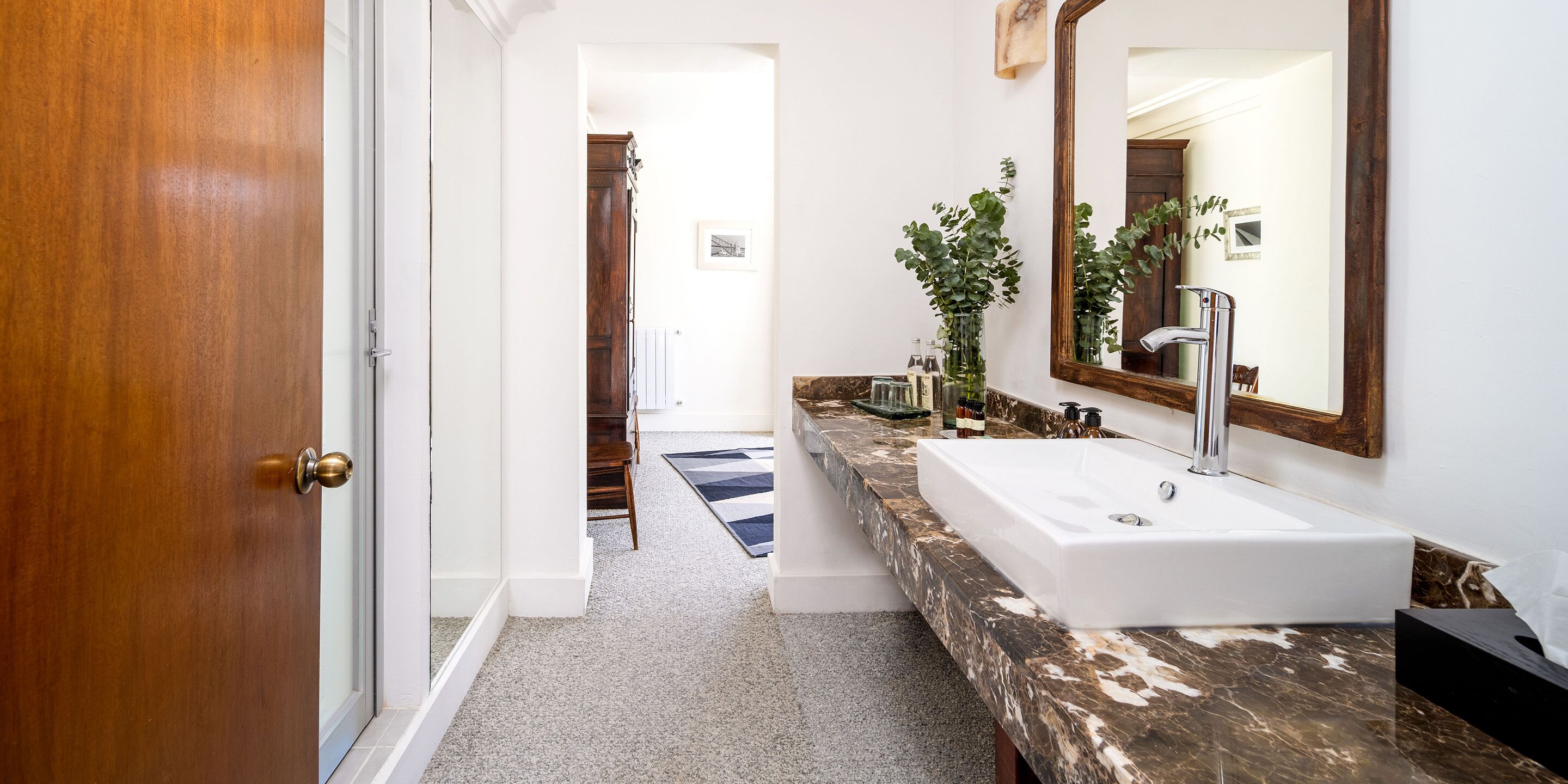 A bathroom with a large sink, a mirror, and a wooden door.
