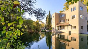 Ein modernes Gebäude mit Spiegelung im Wasser, umgeben von Grünflächen.