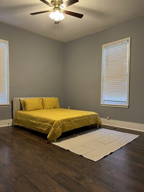 A bedroom with a bed, a ceiling fan, and two windows with blinds. - Spacious Bungalow in Heart of Overton Square! (Memphis)