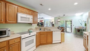 Una cocina amplia con armarios de madera, microondas, estufa y lavavajillas.