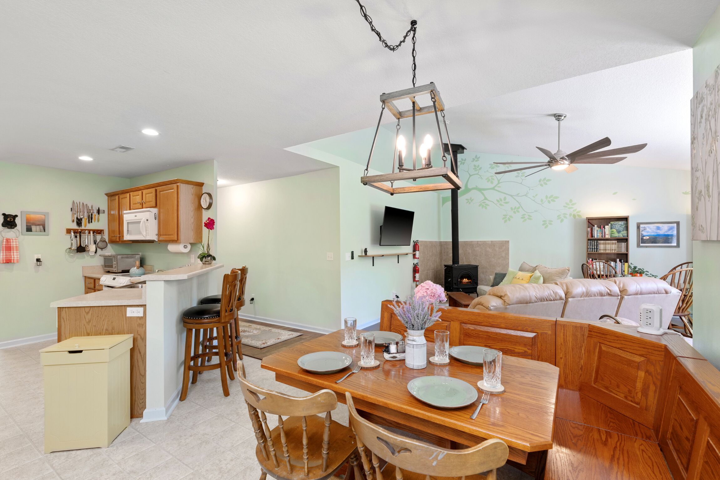 Una cocina amplia con armarios de madera, microondas integrado y comedor con mesa de madera para cuatro comensales.
