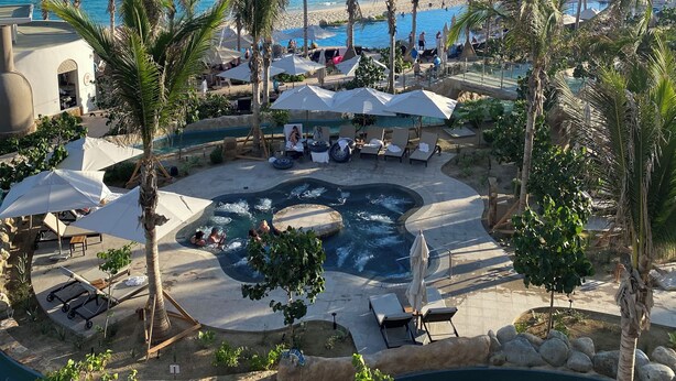 Ein Resort mit Poolbereich, Palmen und Blick auf den Ozean.