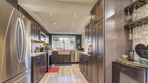 Una cocina moderna con electrodomésticos de acero inoxidable, armarios de madera y una pizarra con un mensaje de bienvenida.
