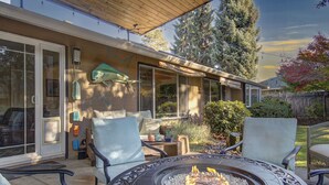 Un patio al aire libre con una chimenea, una zona de estar y una sección cubierta con una mesa y sillas.