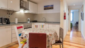 Una cucina moderna con mobili bianchi, una cappa in acciaio inossidabile e un piano di lavoro con bollitore e tostapane.