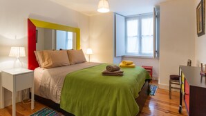 Una camera da letto con un letto, lampade da comodino, una finestra e una scrivania.