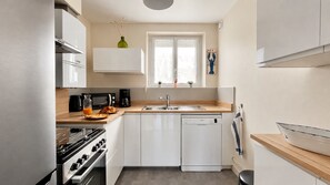 Eine kompakte Küche mit Herd, Backofen, Mikrowelle, Kaffeemaschine und Geschirrspüler.