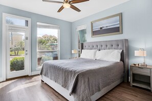Un dormitorio con una cama grande, un ventilador de techo, vista por la puerta y un cuadro en la pared.