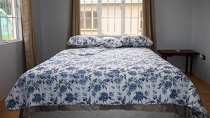 A bedroom with a bed, a window with curtains, and a small table.
