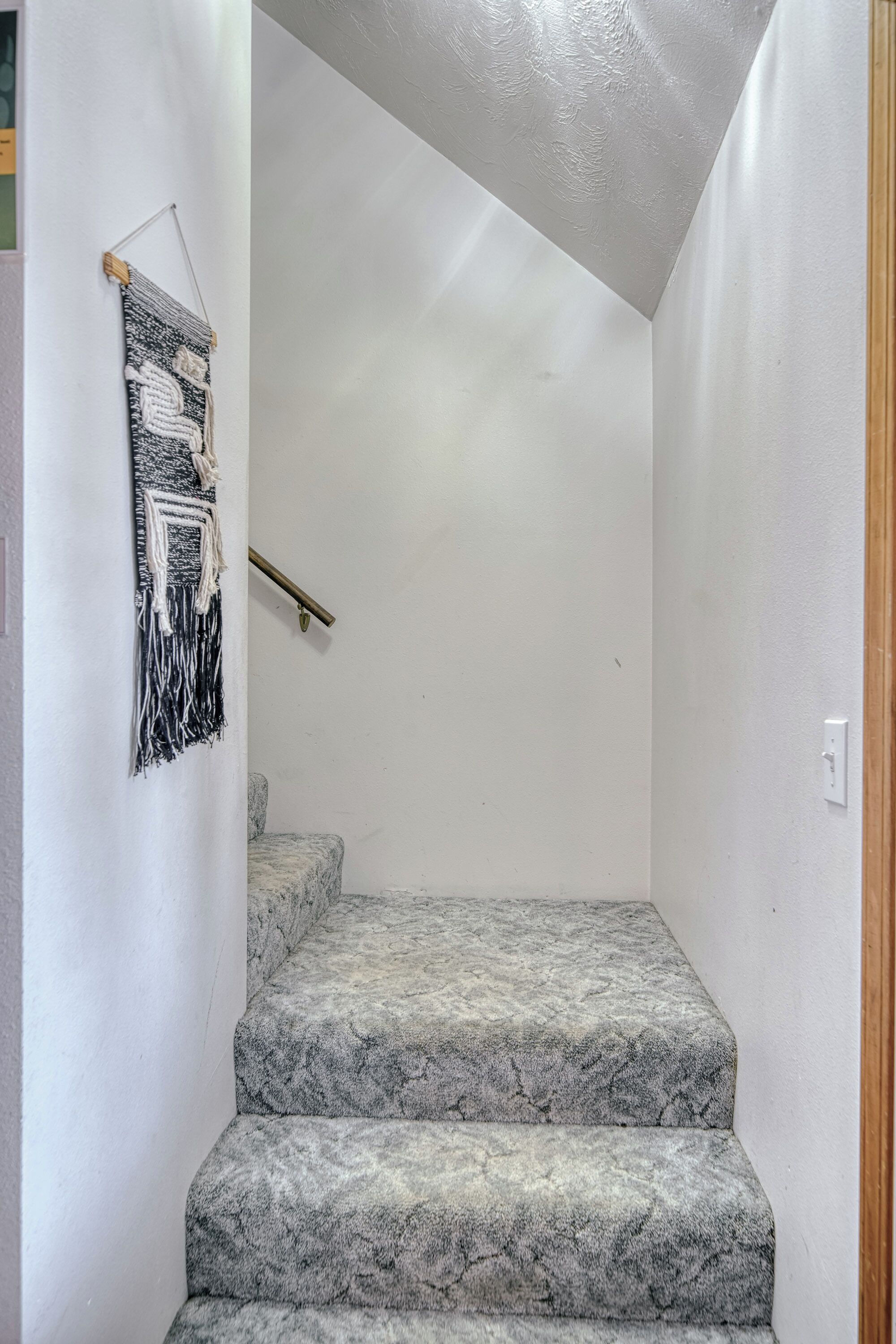 Eine Treppe mit Handlauf und einer Wanddekoration aus Makramee.