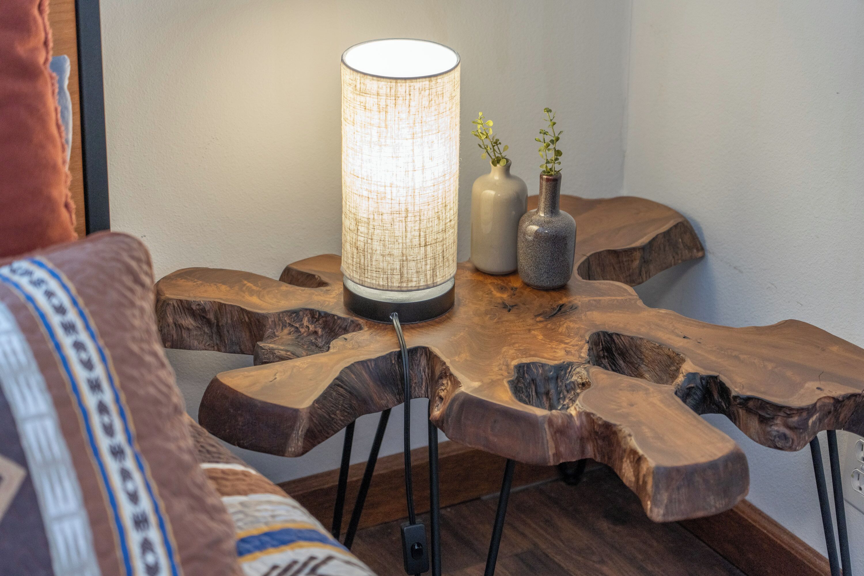 A wooden table with a woven lamp and two vases.