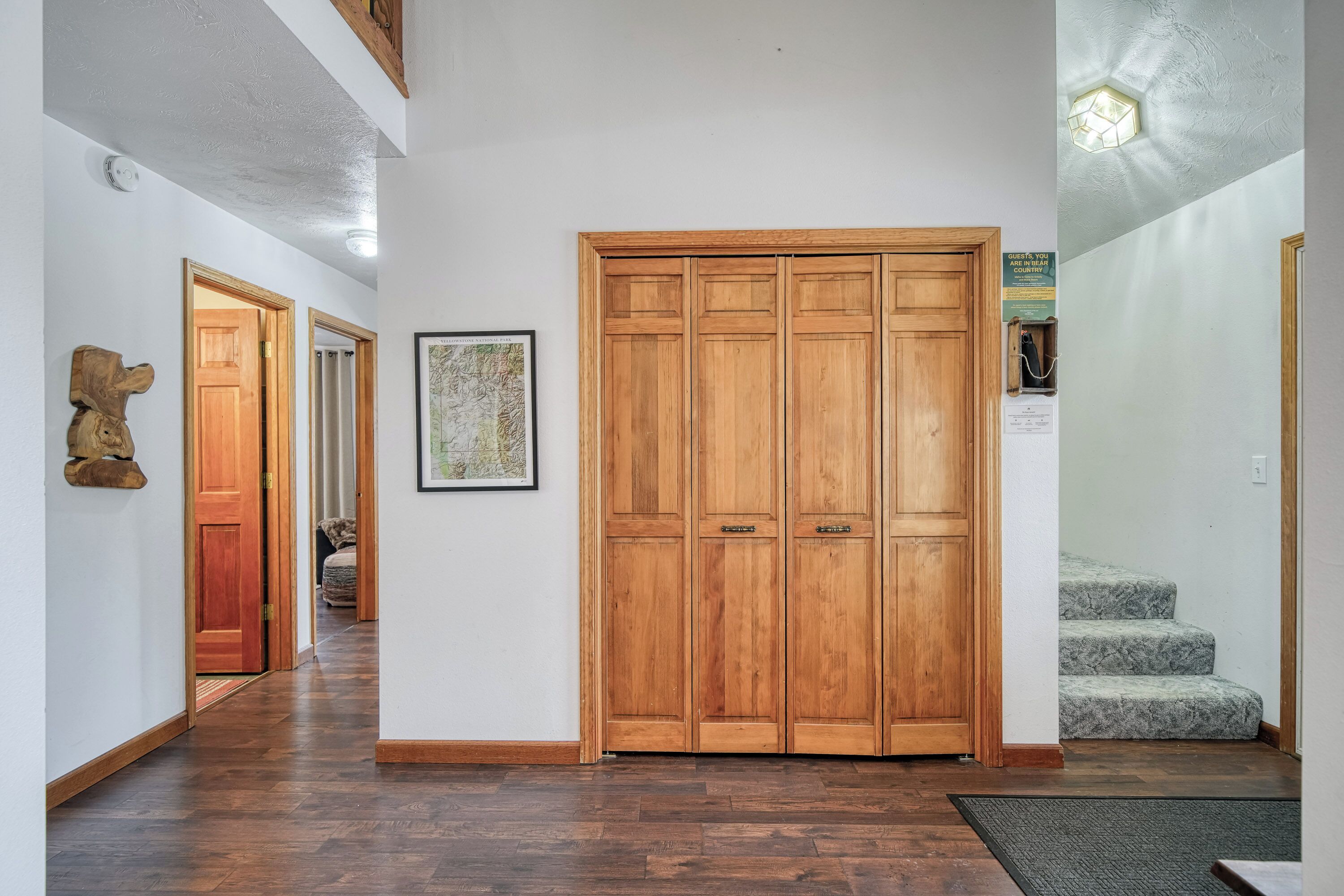 A hallway with wooden doors, a framed map, and a staircase.