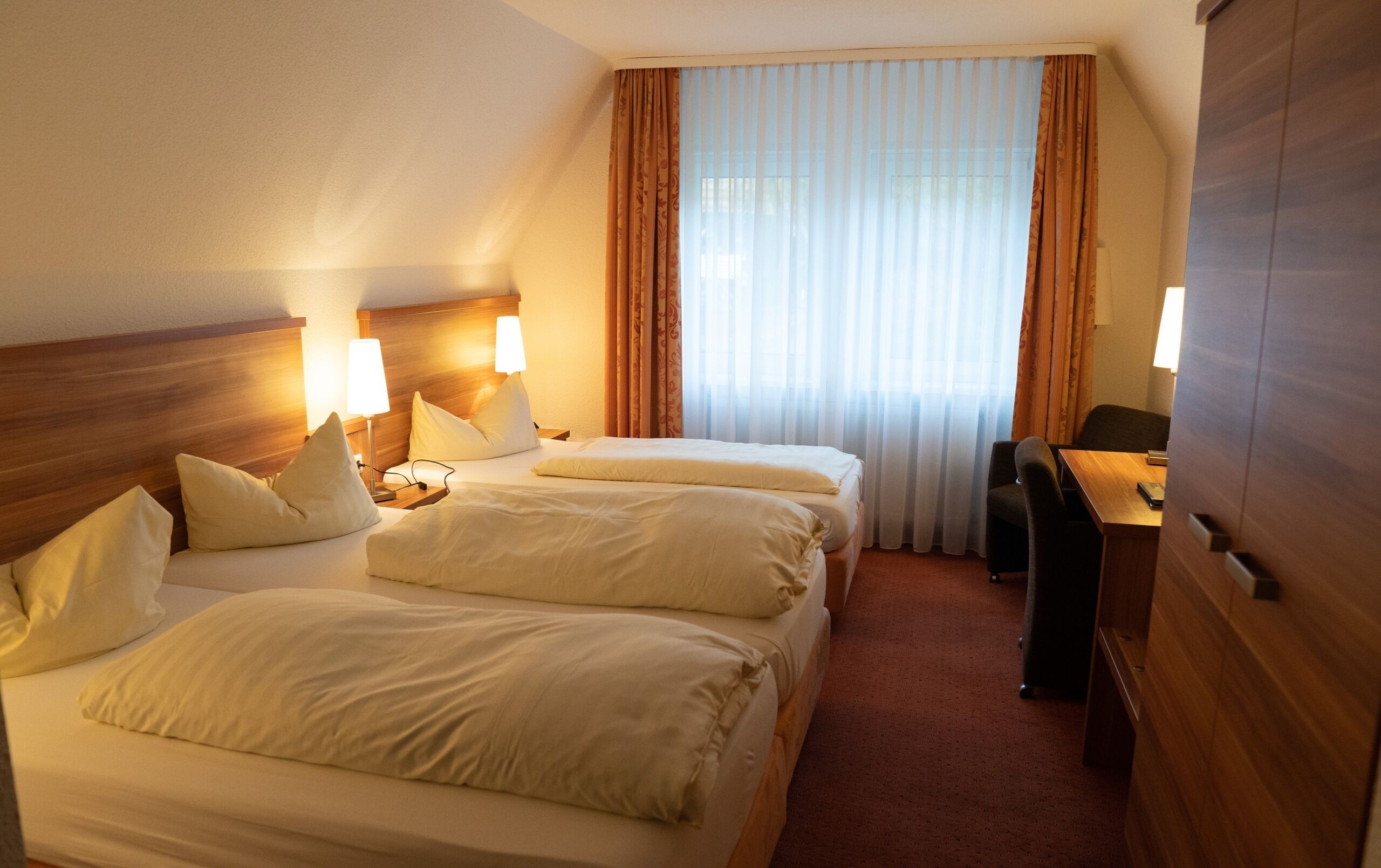 A hotel room with two beds, a desk, and a chair.