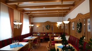 Un restaurant avec des poutres en bois, des banquettes rouges et des tables recouvertes de nappes blanches.