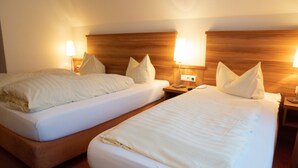 Two single beds with wooden headboards, white linens, and bedside lamps. - Hotel Jägerhof (Bad Hersfeld)
