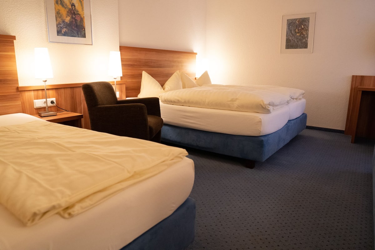 Een hotelkamer met twee bedden, een houten hoofdeinde, een nachtkastje met een lamp en een stoel.