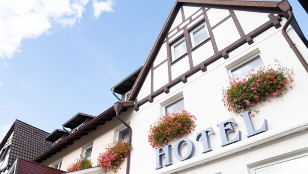 Un hôtel à la façade traditionnelle, avec des éléments en bois apparent et des ornements, de nombreuses fenêtres et des jardinières fleuries.