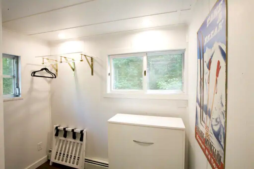 A room with a radiator, a white cabinet, and a window with a view of trees.