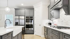 A modern kitchen with grey cabinets, stainless steel appliances, and a white countertop. - BeachView-Arcade-Walk to Beach-Restaurants-Casino (Gulfport)