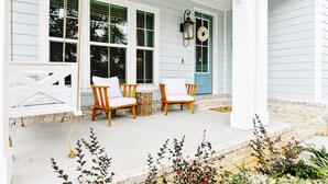 A porch with two wooden chairs and a small table, a swing, and a decorative lantern. - BeachView-Arcade-Walk to Beach-Restaurants-Casino (Gulfport)